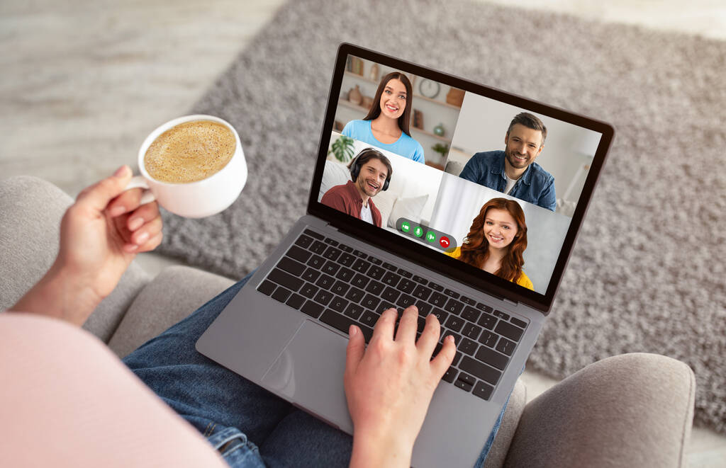 Unrecognizable woman having video chat with friends and drinking coffee
